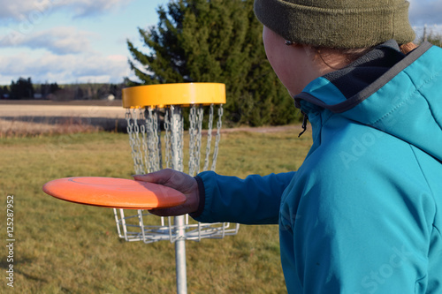 Young woman aiming disc golf to target.