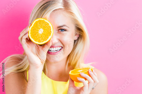Happy young woman holding orange halves