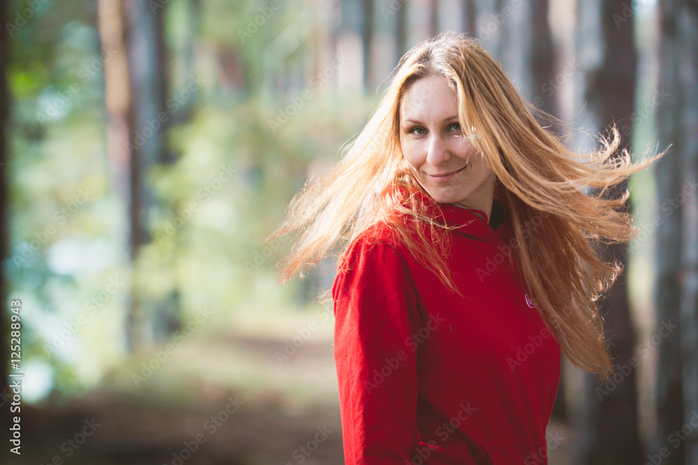 Young cheerful female model at summer forest in red suit with waving hair Young cheerful female model at summer forest in red suit with waving hair