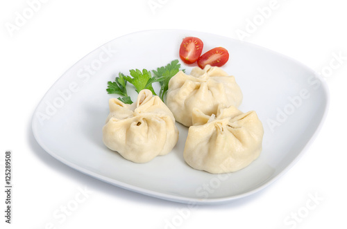 Buryat Manti served on a white plate with tomatoes and herbal on a white background
