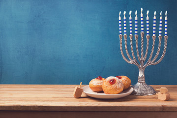 Hanukkah holiday sufganiyot and menorah on wooden table over vintage background