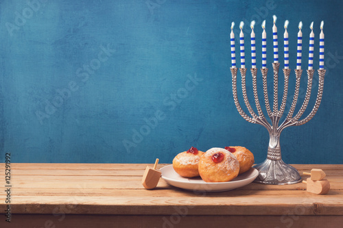 Hanukkah holiday sufganiyot and menorah on wooden table over vintage background
