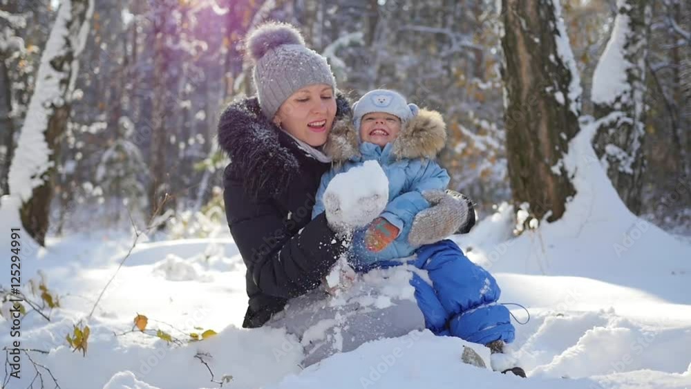 A girl with a child playing with snow in the park in a Sunny day