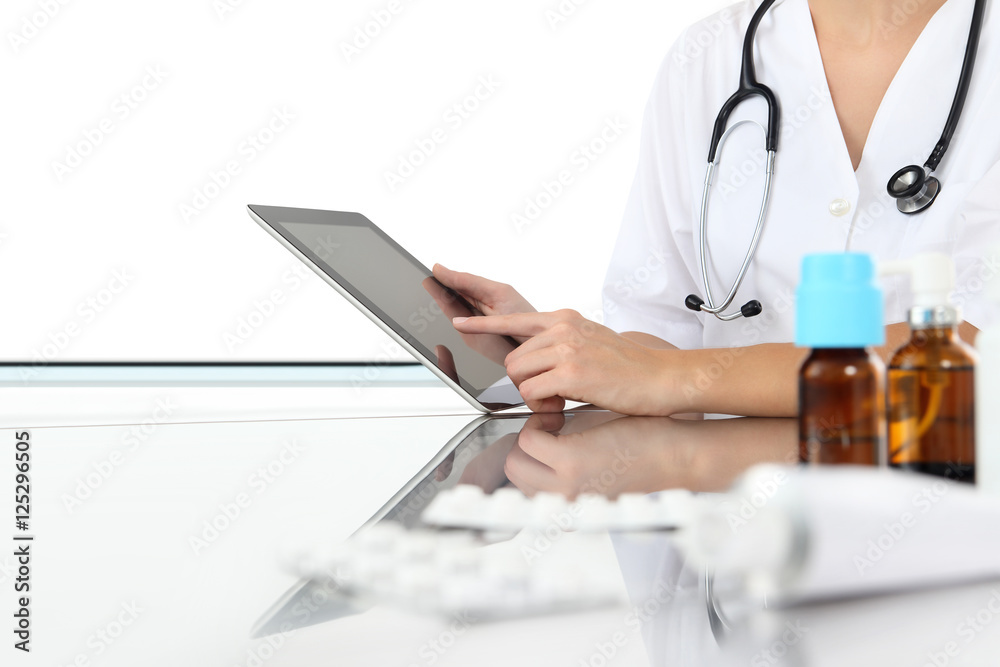 doctor using tablet in medical office with drugs on desk doctor using tablet in medical office with drugs on desk