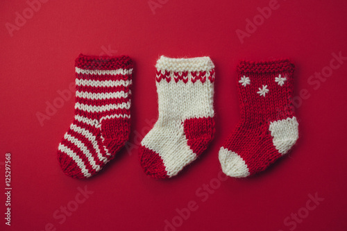 Mini Christmas Stockings.Three red and white wool Christmas stockings on red background.