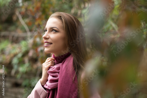 Portrait of young woman in pink topcoat at autumn day