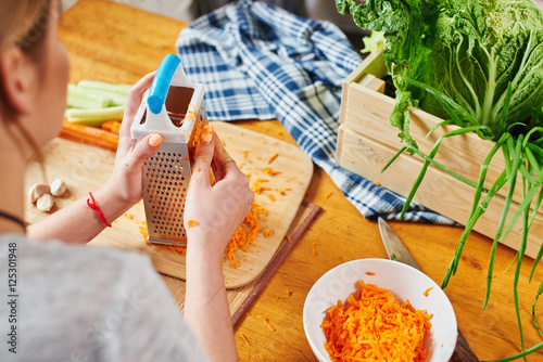 Girl grate the carrots on a wooden Board