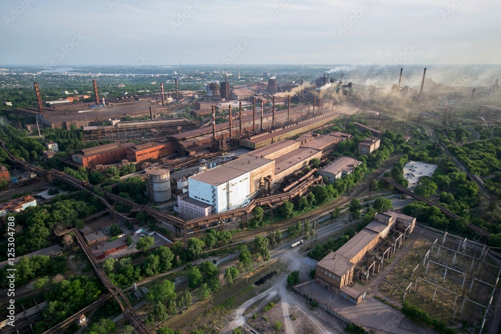 Industrial landscape in Ukraine. Steel factory with smog at sunset. Pipes with smoke. Metallurgical plant. steelworks, iron works. Heavy industry. Ecology problems, atmospheric pollutants.