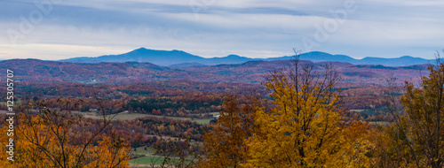 Green Mountains in Vermont with the rolling hills in foreground in full fall foliage colors 
