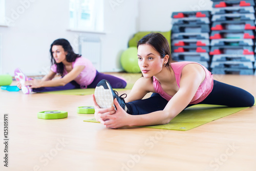 Woman doing cross split exercise working out her hip abductor muscles and ligaments. Fit female athlete stretching splits in gym. photo