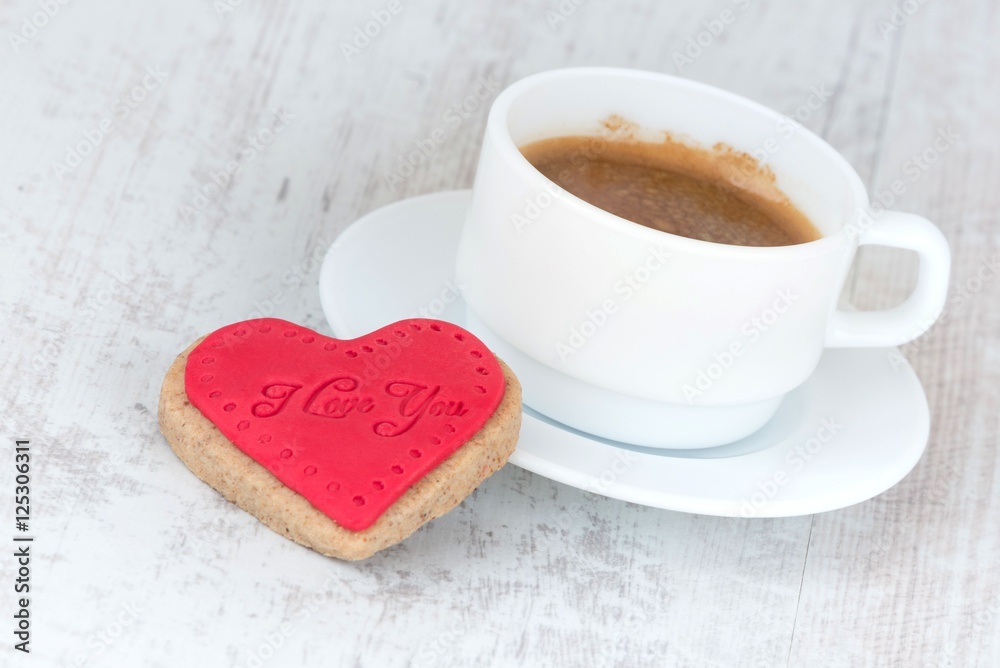 Valentines day background. A heart shaped cookie and a cup of coffee over a white wood rustic background. Valentines day background. A heart shaped cookie and a cup of coffee over a white wood rustic background.