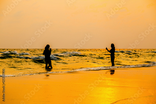 Silhouette photo. people taking picture on the beach at sea and sunset