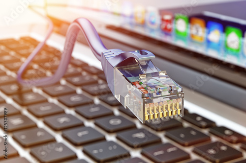 Wire network connection and internet communication technology concept, closeup view of ethernet cable plug connector on computer laptop keyboard