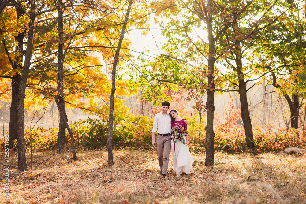 Stylish and romantic caucasian couple have a walk in beautiful autumn park. Love, relationships, romance, happiness concept. Bouquet in girl's hands.