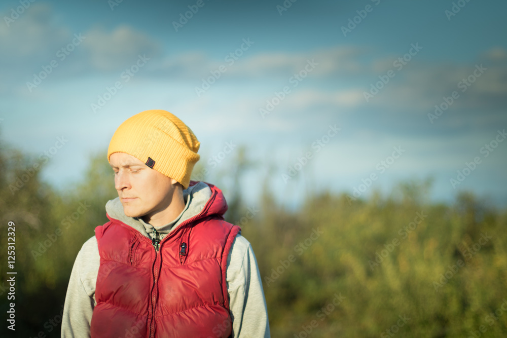 Young hipster male student in yellow hat and ren jacket outdoors Young hipster male student in yellow hat and ren jacket outdoors