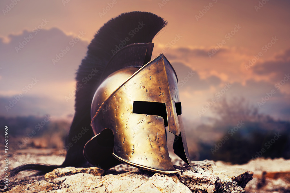 Fototapeta premium Spartan helmet on ruins with sunset sky.