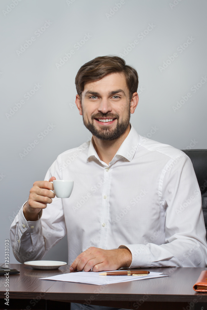 Young handsome businessman smiling with cup of coffee Young handsome businessman smiling with cup of coffee