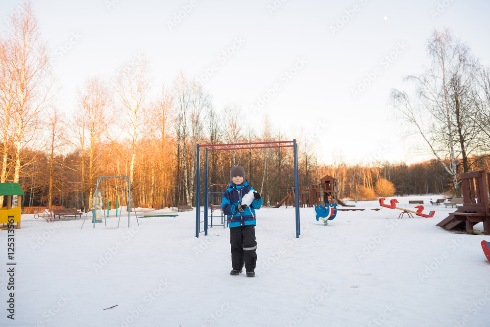 child boy on winter walk with giant snowball 