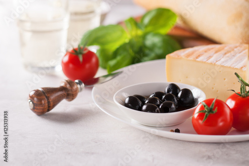 Italian appetizers, view from above - bread ciabatta, olives, tomatoes, cheese, pepper, fresh basil and wine, ready for cooking with copy space