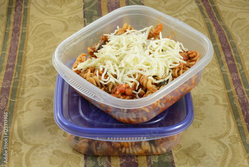 Putting casserole leftovers into plastic containers for work lunches or for freezing with shredded cheese as extra photo