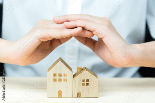 Female hand cover wooden house. House protection concept