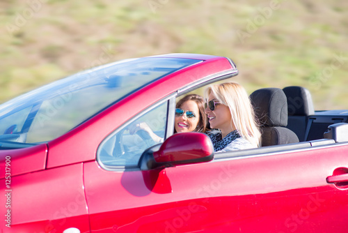 Two beautiful young women sitting in the car and enjoy in driwing