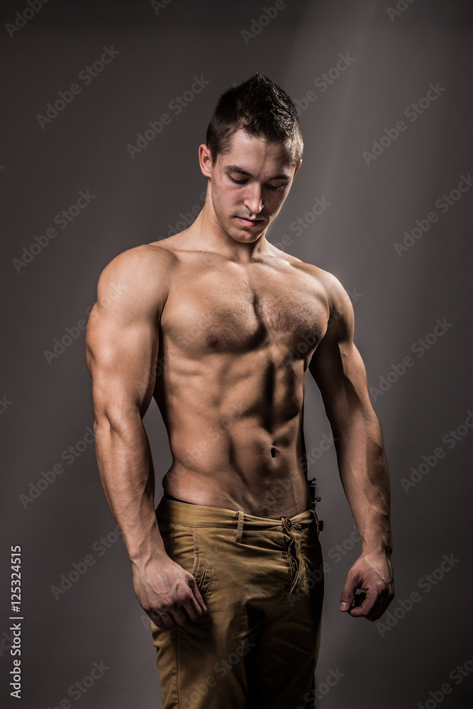 young bodybuilder posing strong upper body pants