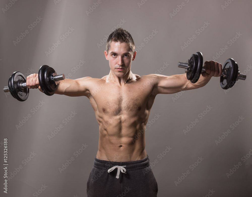 young man bodybuilder looking down, dumbbells exercise.