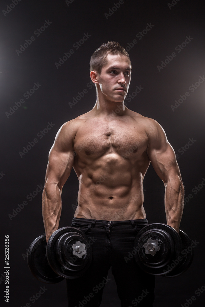 young man bodybuilder looking sideways holding dumbbells