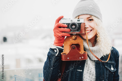 Smiling curly blond girl with retro film camera