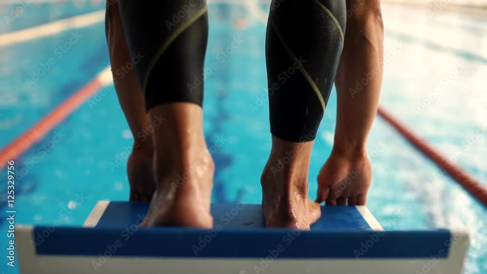 Professional male swimmer jumping off the starting block into the pool. Professional male swimmer jumping off the starting block into the pool.