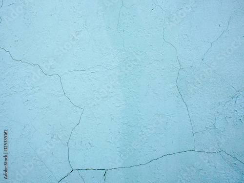 The old plastered background on a building wall with cracks and chips