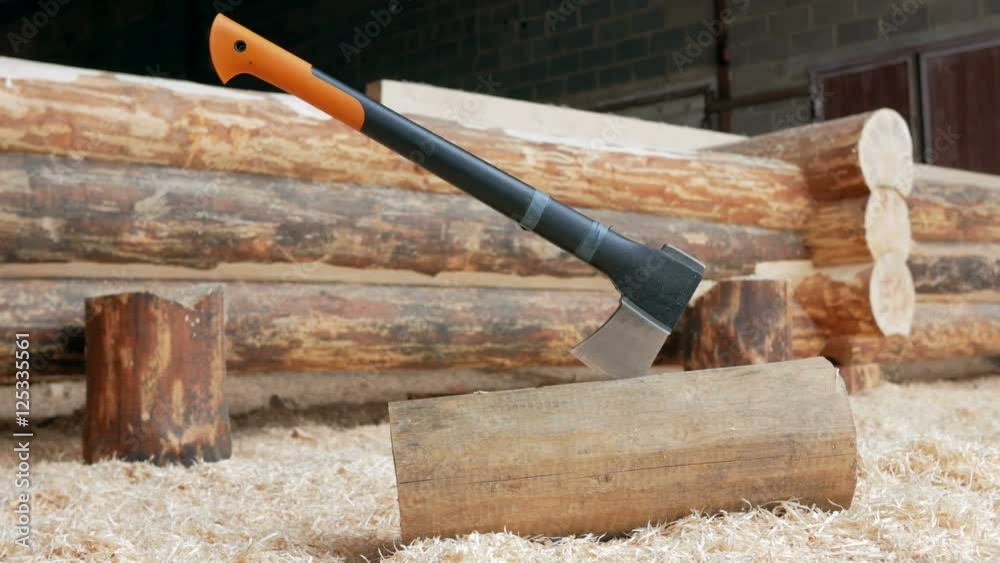 Modern black axe lies in a large pile of sawdust. Close-up of the cutting part of the Axe. moving the camera Modern black axe lies in a large pile of sawdust. Close-up of the cutting part of the Axe. moving the camera