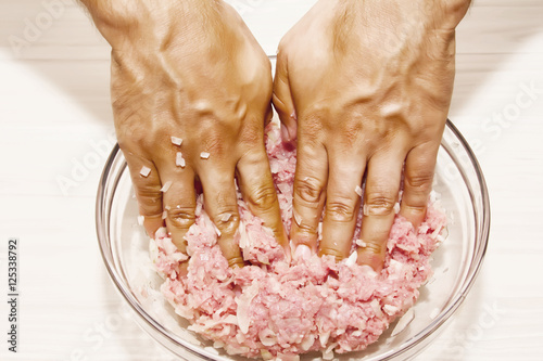Pair of hand mixing raw ground beef mixture preparing to make fresh gourmet hamburgers