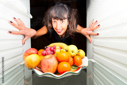 Woman opens the fridge with fruit