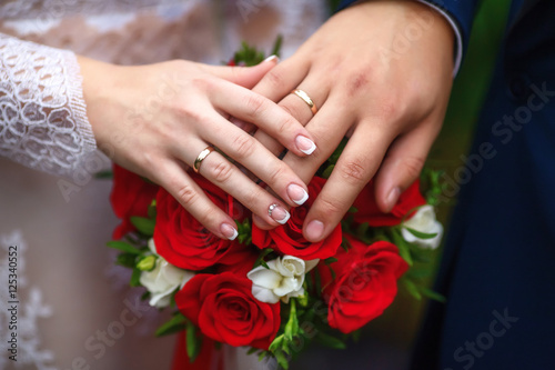 Hands of bride and groom on wedding bouquet. Marriage concept