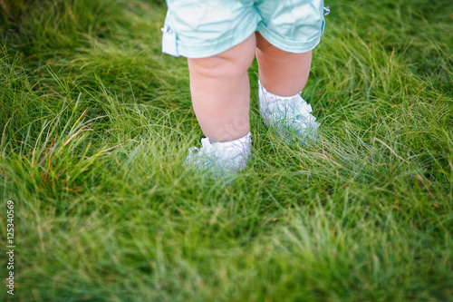 First steps of little girl in summer park on grass