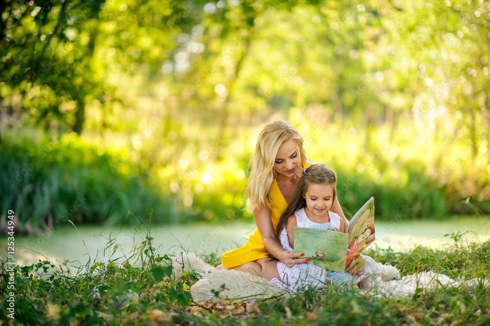 mother reads the book in the daughter on a grass