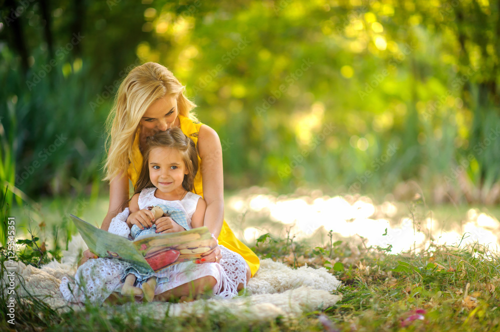 mother reads the book in the daughter on a grass