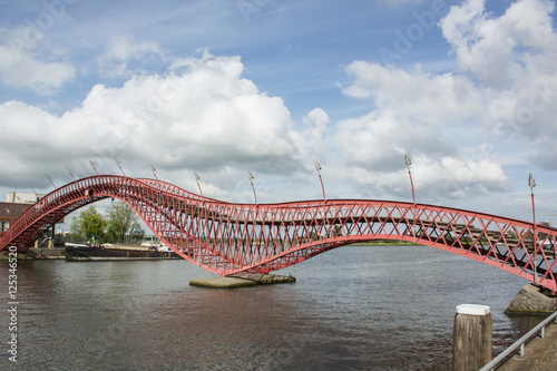 Long red modern bridge Python in Amsterdam in the day over the river