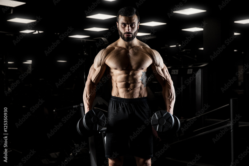 Handsome man with big muscles, posing at the camera in the gym