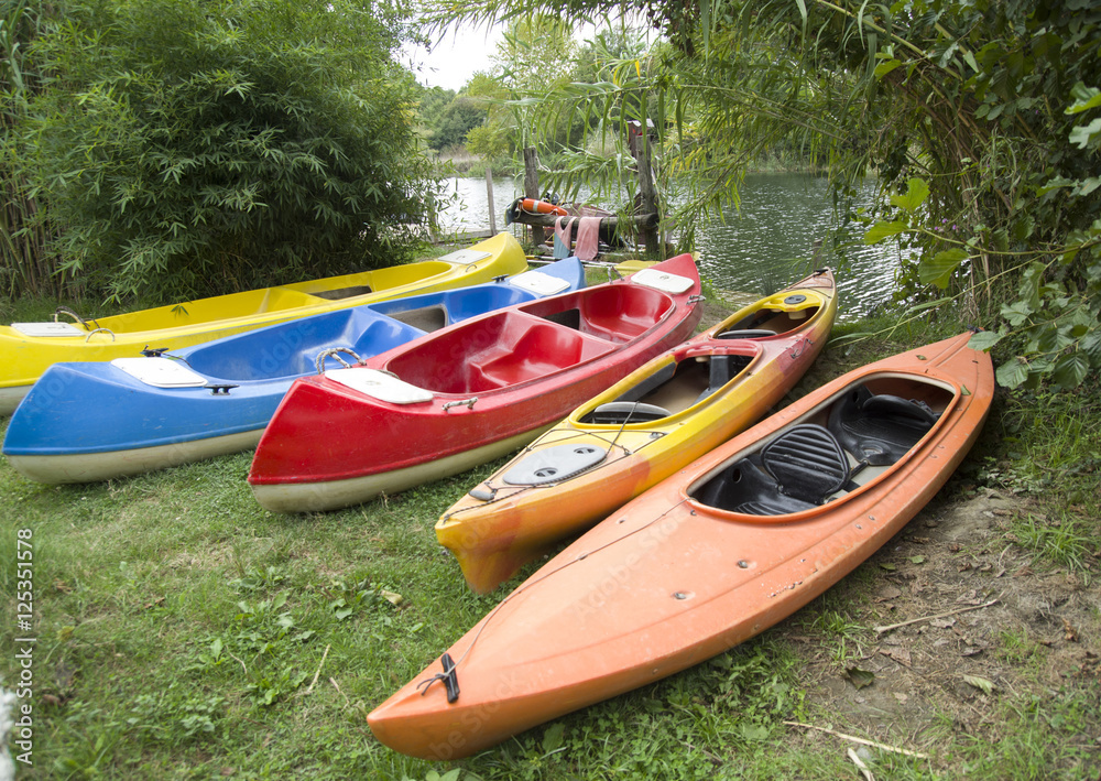 Several single and double kayaks and boats on the riverside Several single and double kayaks and boats on the riverside