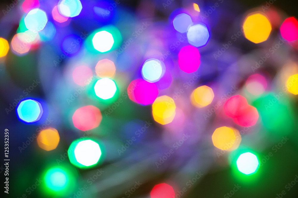 Colorful Christmas lights on dark wooden background, blurred