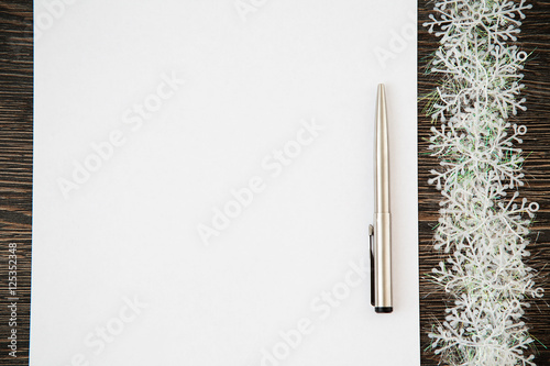 Paper note book with white pages and pen lying on wooden background. New Year