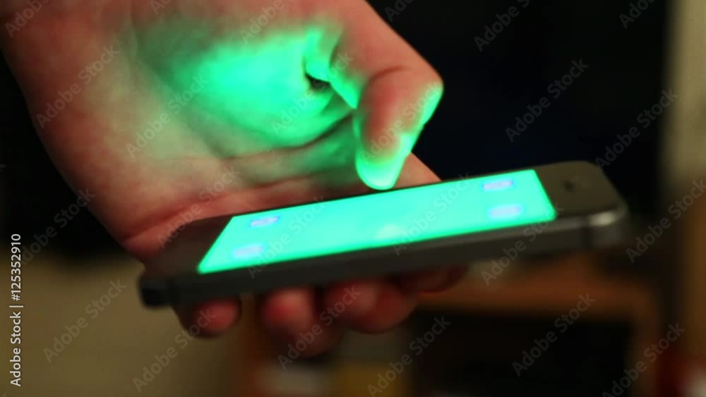 Main et smartphone sur fond vert pour incrustation - lueur verte