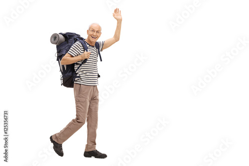 Elderly hiker walking and waving at the camera