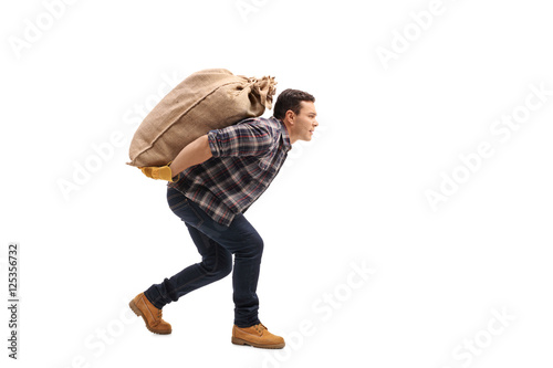 Male agricultural worker carrying burlap sack on his back