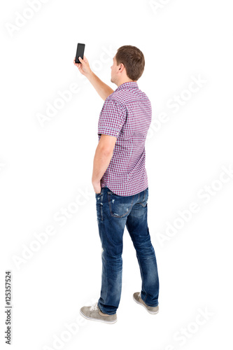 Back view of standing young men and using a mobile phone.