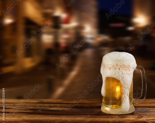 cold mug of beer with foam on the background of the street