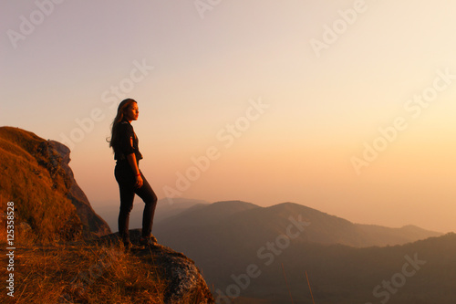 Hipster young girl with backpack enjoying sunset on peak of foggy mountain. Tourist traveler on background view mockup. Hiker looking sunlight in trip in Thailand country  mock up text.
